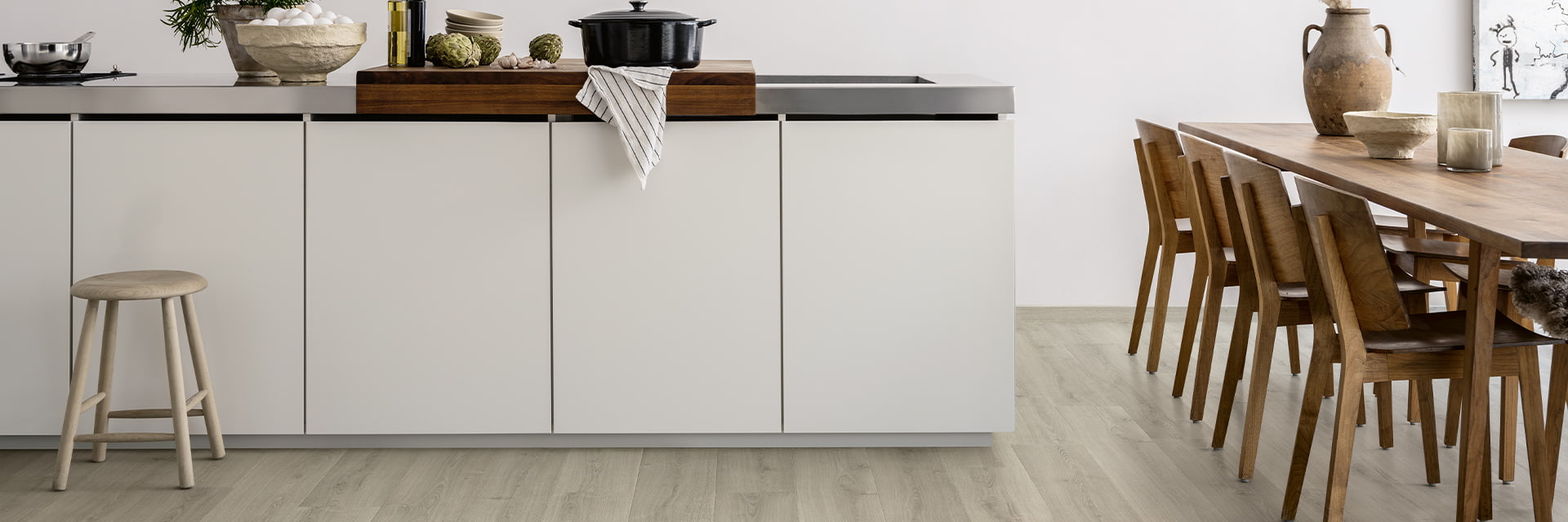 Hvitt kjøkken med grått laminatgulv og brunt kjøkkenbord